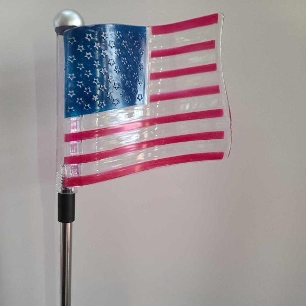 Decorative American flag on a pole against a plain wall