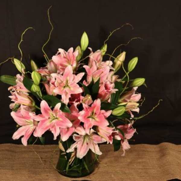 Pink lilies arranged in a glass vase with unopened buds