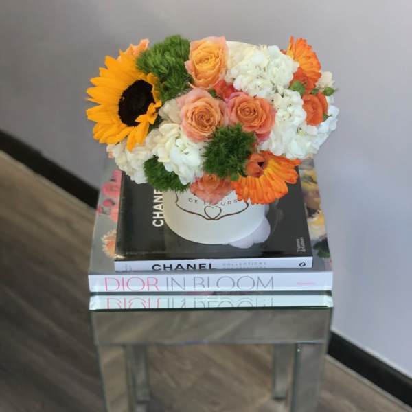 Bouquet of sunflowers, roses, and white hydrangeas in a white hat box