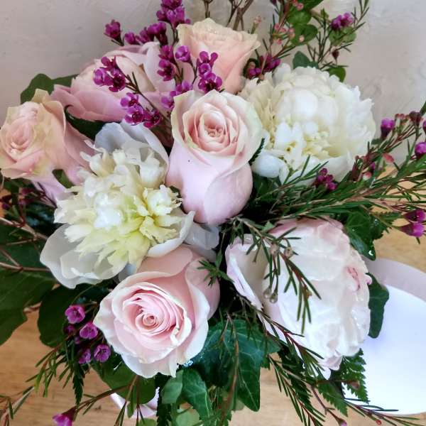 Pink roses and white blooms with purple filler flowers in a bouquet