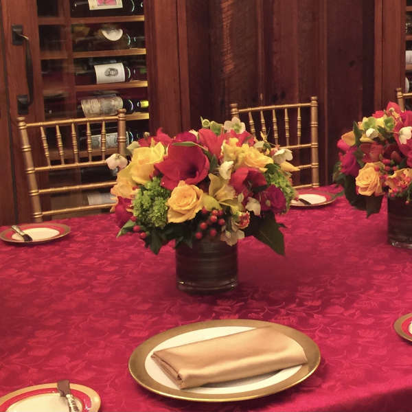 Red and yellow floral centerpieces in dark vases on a banquet table