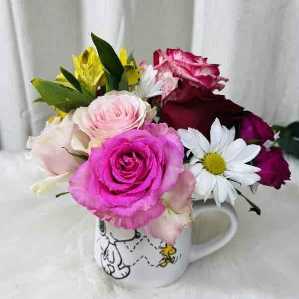 Mixed roses and daisies arranged in a Snoopy mug