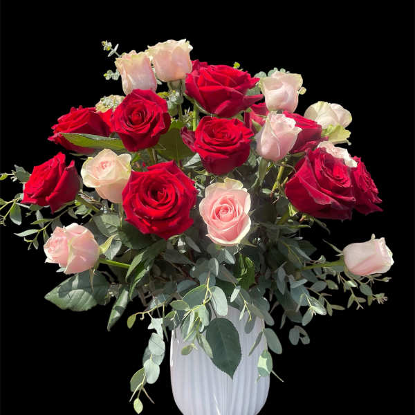 Red and blush roses arranged in a white vase
