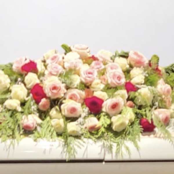 Low arrangement of pink and white roses with greenery