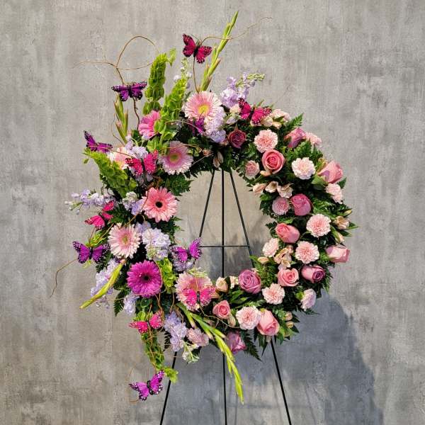 Large floral wreath with pink and lavender flowers on a black stand