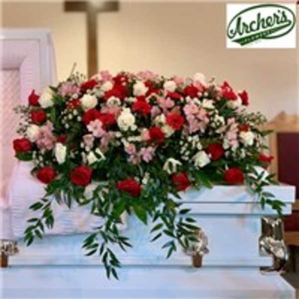 Large red, white, and pink floral spray on a white casket
