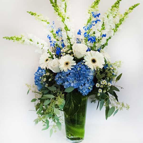 Blue and white floral arrangement in a tall glass vase