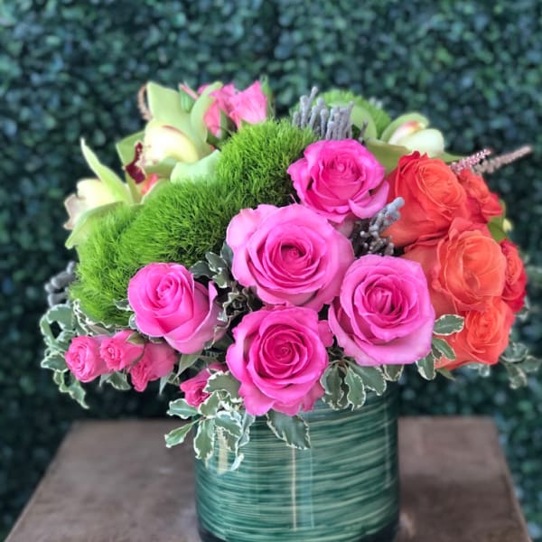 Bouquet of pink and orange roses in a green glass vase