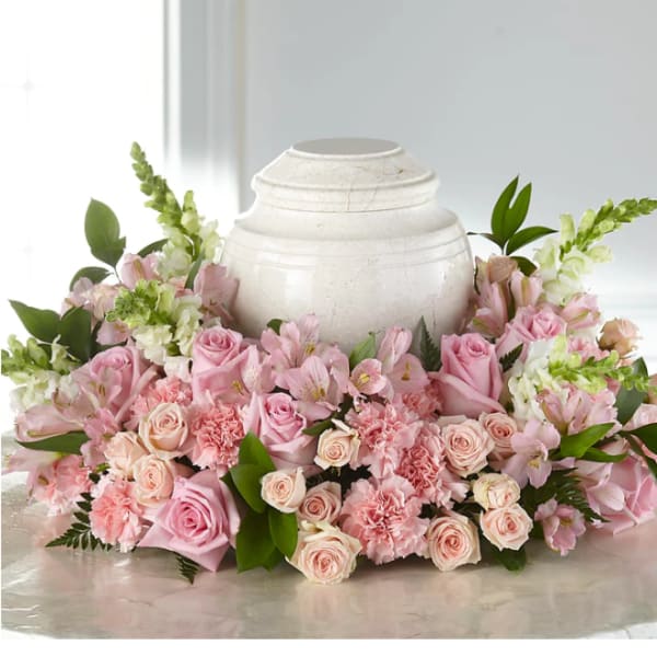 Pink roses and carnations arranged around a white urn