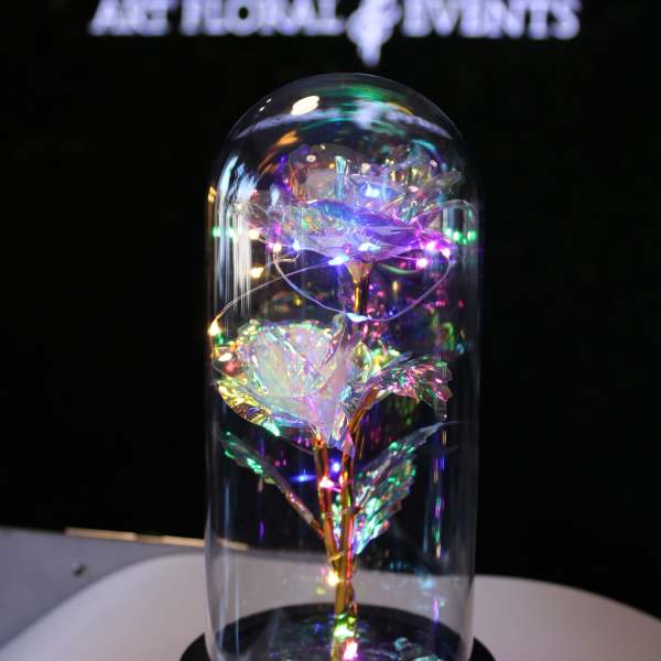 Iridescent decorative roses under a glass dome on a black base