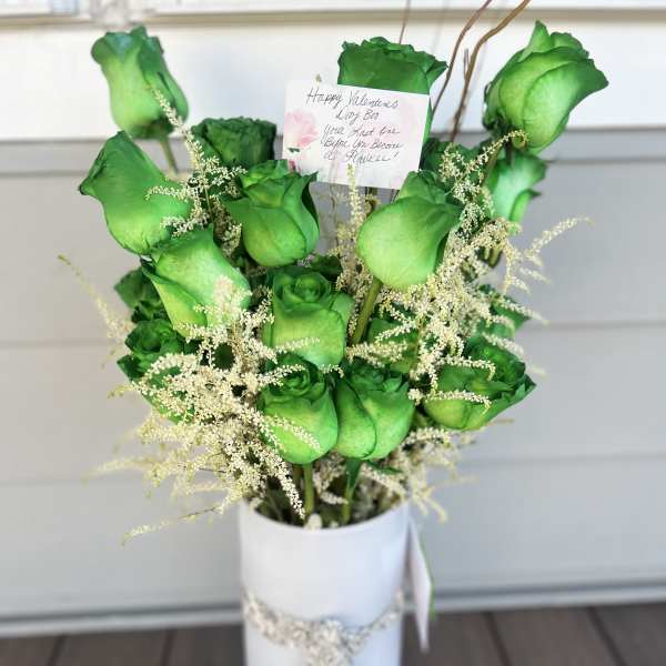 Bouquet of green roses in a white vase with a handwritten card