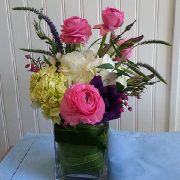 Pink and white flowers arranged in a clear glass vase.