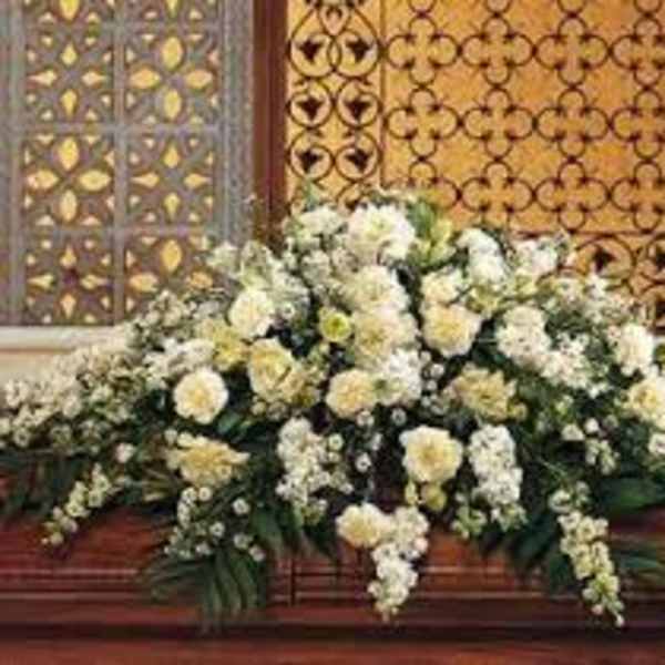Large white floral arrangement with cascading blooms on a wooden platform