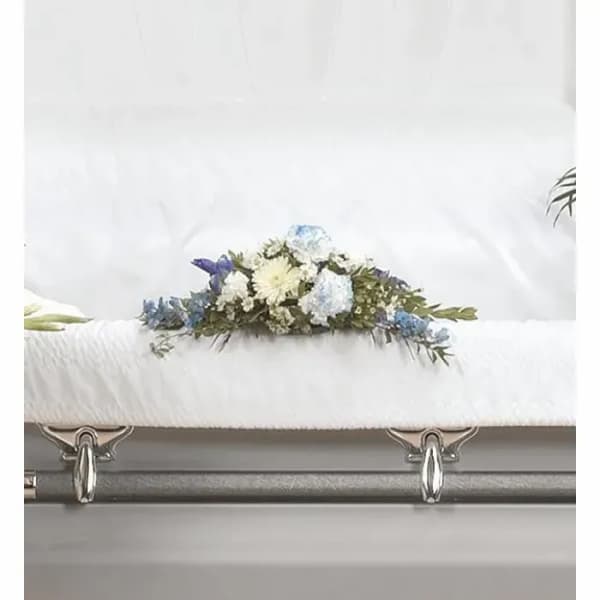 White casket with a blue and white floral spray on top