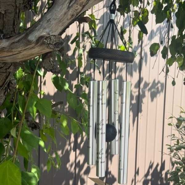 Silver wind chime hanging among tree branches