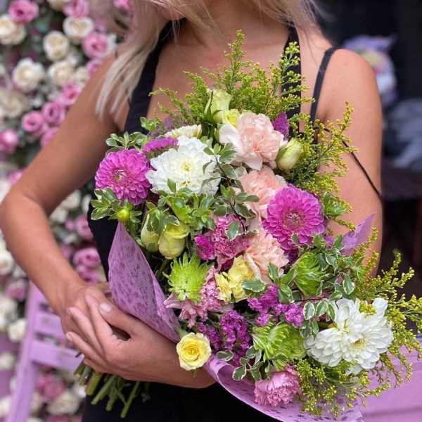 Woman holding a mixed bouquet of pink, white, and yellow flowers
