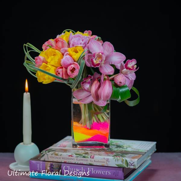 Pink and yellow tulips with pink orchids in a glass vase