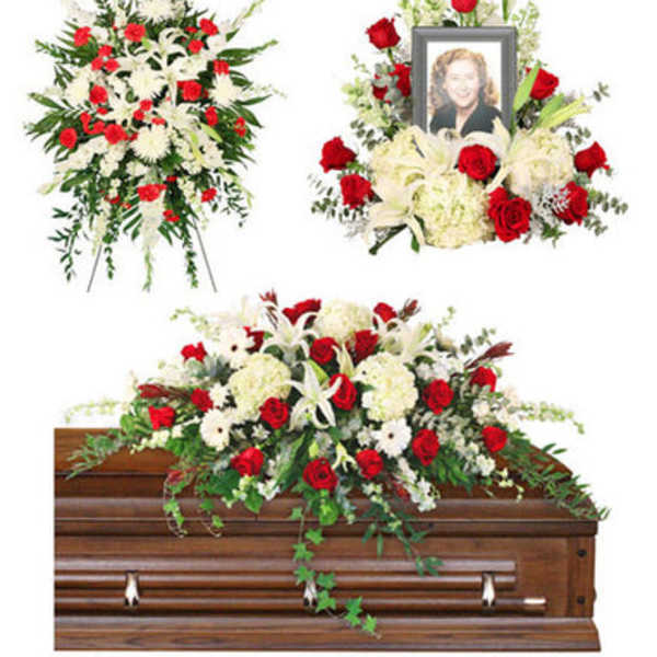 Funeral floral tributes with red and white flowers around a casket and framed photo