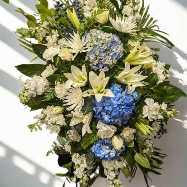 Large floral standing spray with blue hydrangeas, white lilies, and white blooms