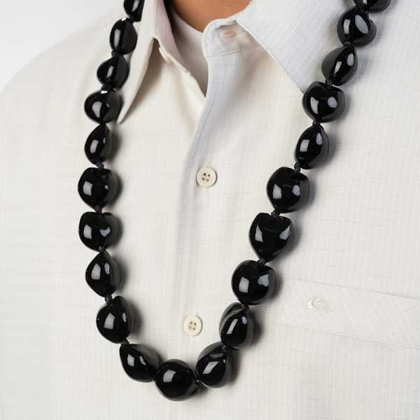 Glossy black beaded lei-style necklace worn over a light button-up shirt