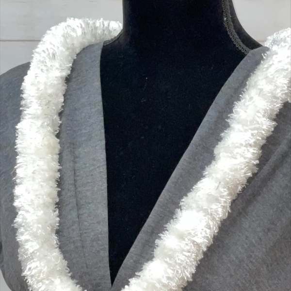 White fluffy lei-style garland displayed on a gray dress form
