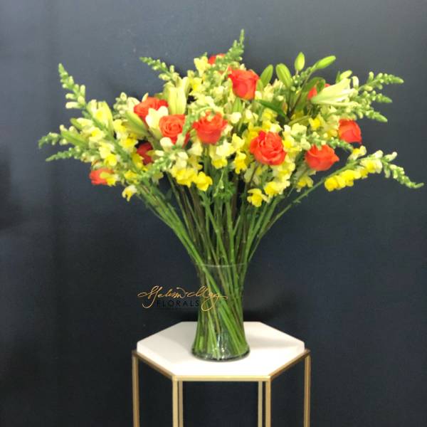 Mixed bouquet of red roses and yellow snapdragons in a glass vase