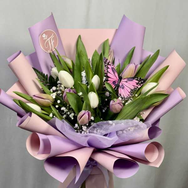Bouquet of white and lavender tulips wrapped in pink and purple paper