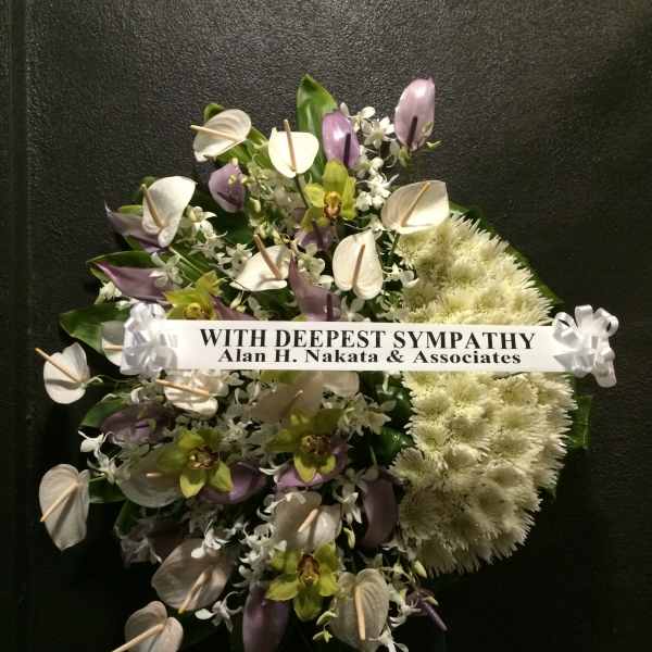 Sympathy wreath with white and purple flowers and a condolence ribbon