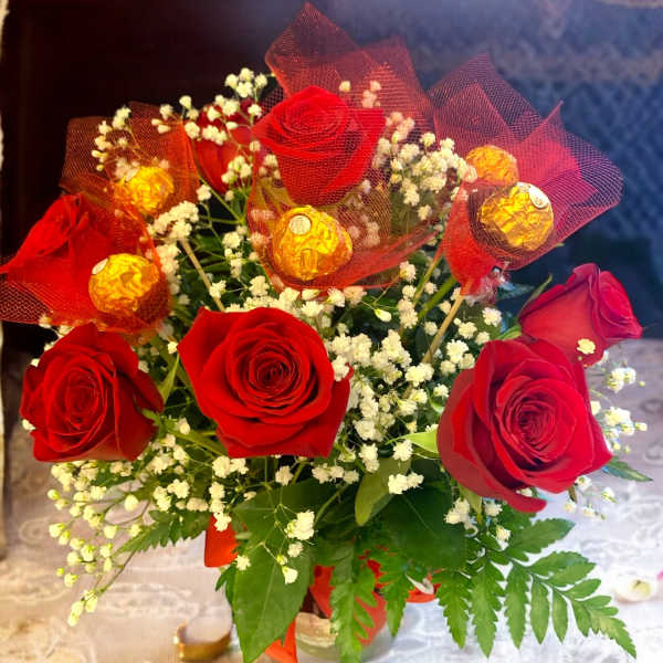 Red roses with baby’s breath and wrapped chocolates in a bouquet