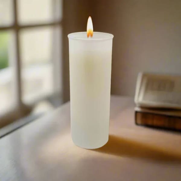 Lit white pillar candle on a table