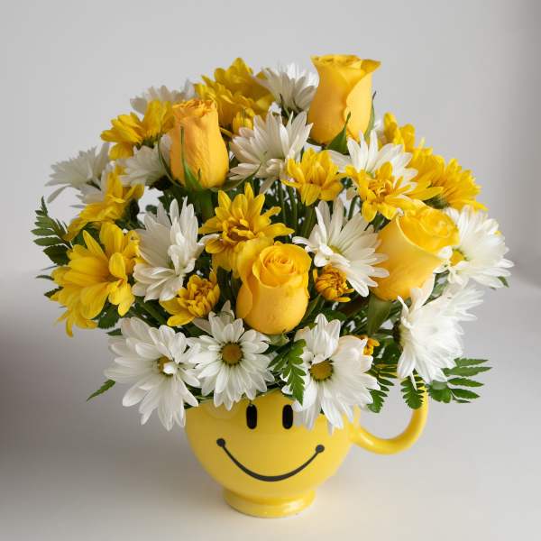 Yellow roses and white daisies in a smiley-face mug