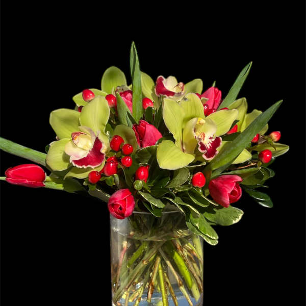 Bouquet of green orchids and red tulips in a clear glass vase
