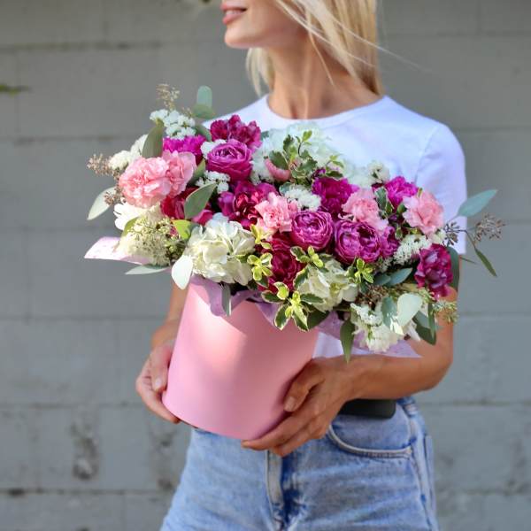 Woman holding a pink box of pink and white flowers