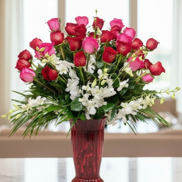 Bouquet of red and pink roses with white orchids in a red vase