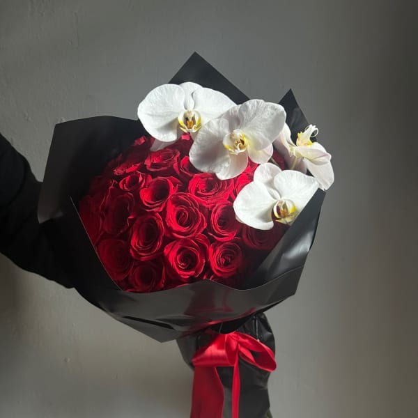 Red rose bouquet with white orchids wrapped in black paper and a red ribbon