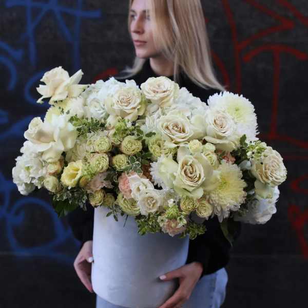 Woman holding a large white floral arrangement in a round box