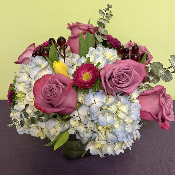 Pink roses and blue-white hydrangeas in a low vase arrangement