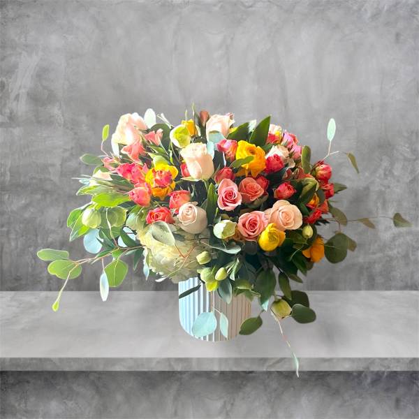 Mixed bouquet of pink, peach, yellow, and white roses in a striped vase