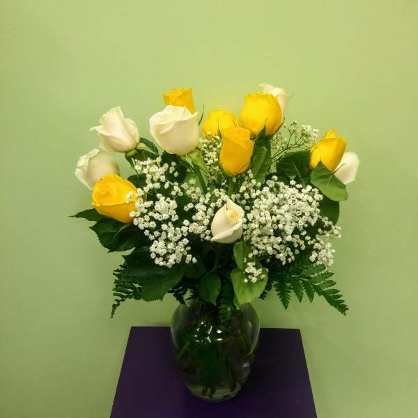 Yellow and white roses in a glass vase with baby's breath