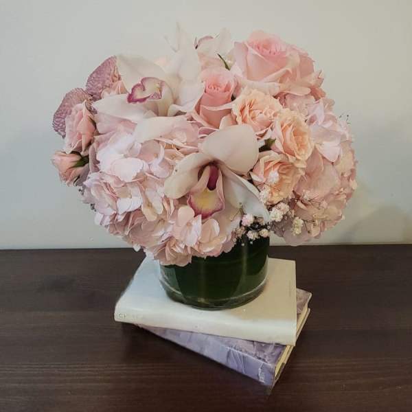 Pink bouquet with roses, hydrangeas, and orchids in a glass vase