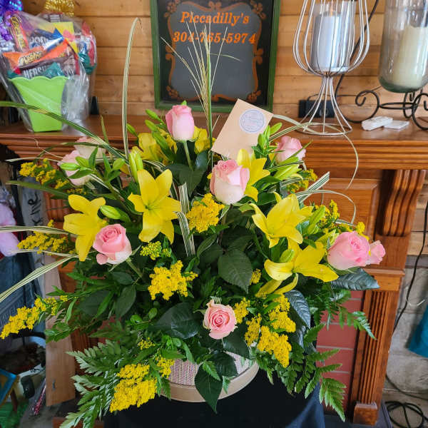 Pink roses and yellow lilies in a round basket arrangement