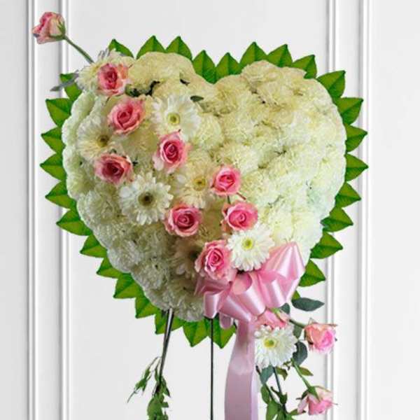 Heart-shaped floral spray with pink roses, white flowers, and a pink ribbon