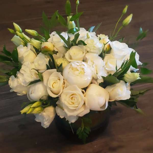 White roses and peonies arranged in a low black vase