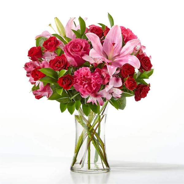 Pink lilies and red roses arranged in a clear glass vase