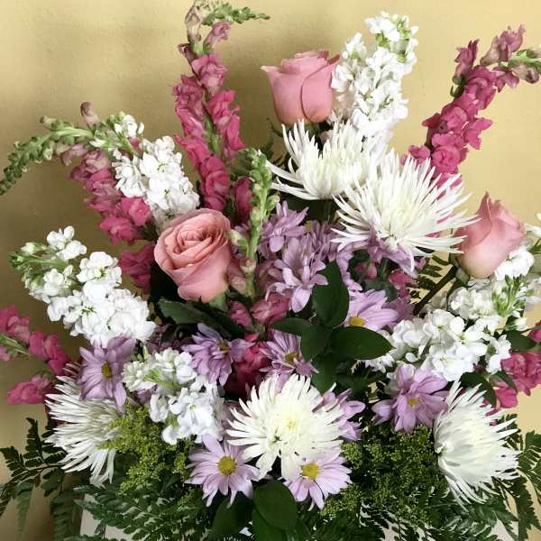 Mixed bouquet of pink roses, white chrysanthemums, and lavender daisies in a white vase