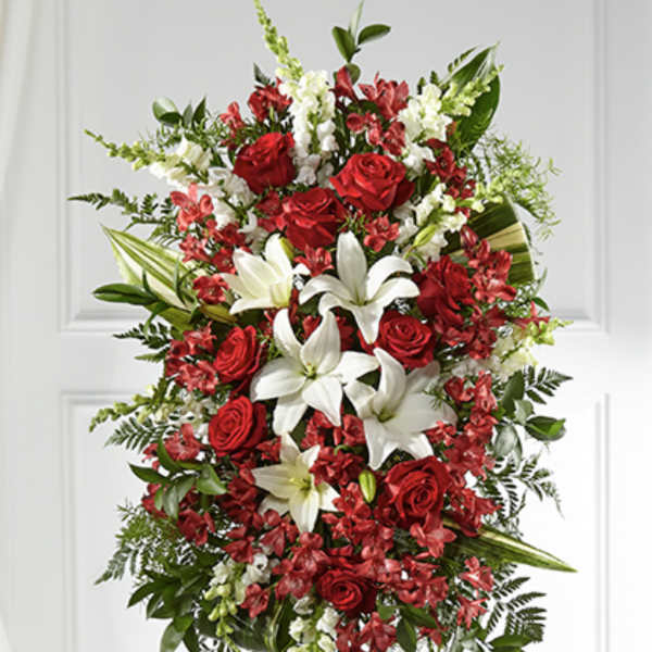 Standing spray of red roses, white lilies, and mixed red and white flowers on an easel.