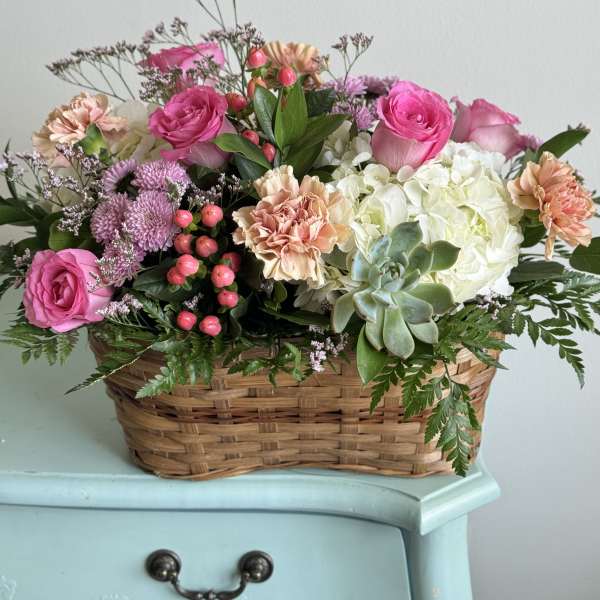 Basket arrangement of pink roses, carnations, hydrangea, and a succulent