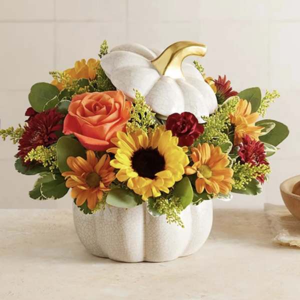 Fall arrangement with sunflowers, orange rose and mums in a white ceramic pumpkin container