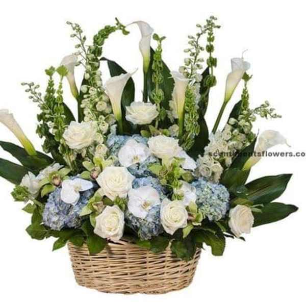 White calla lilies and roses with blue hydrangeas in a wicker basket