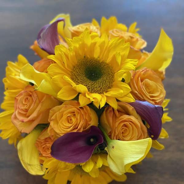 Bouquet of sunflowers, orange roses, and purple calla lilies